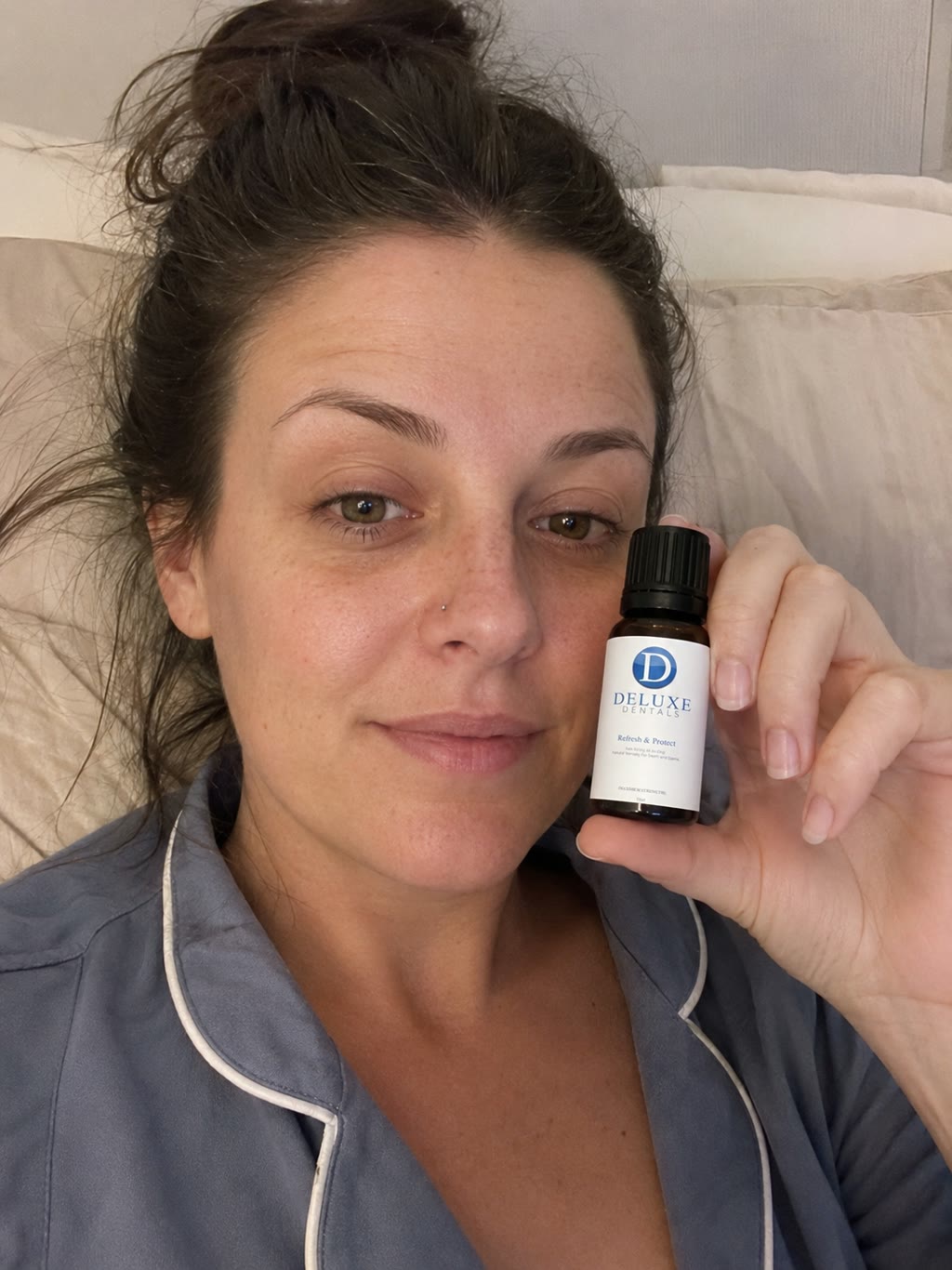 Customer holding the Refresh & Protect bottle while sitting up in bed.