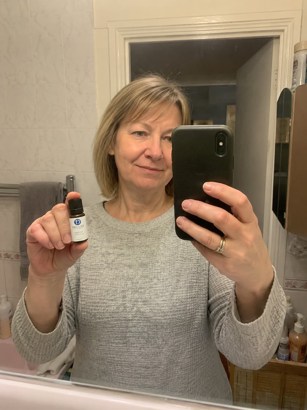 Customer holding the Refresh & Protect bottle in a bedroom setting.