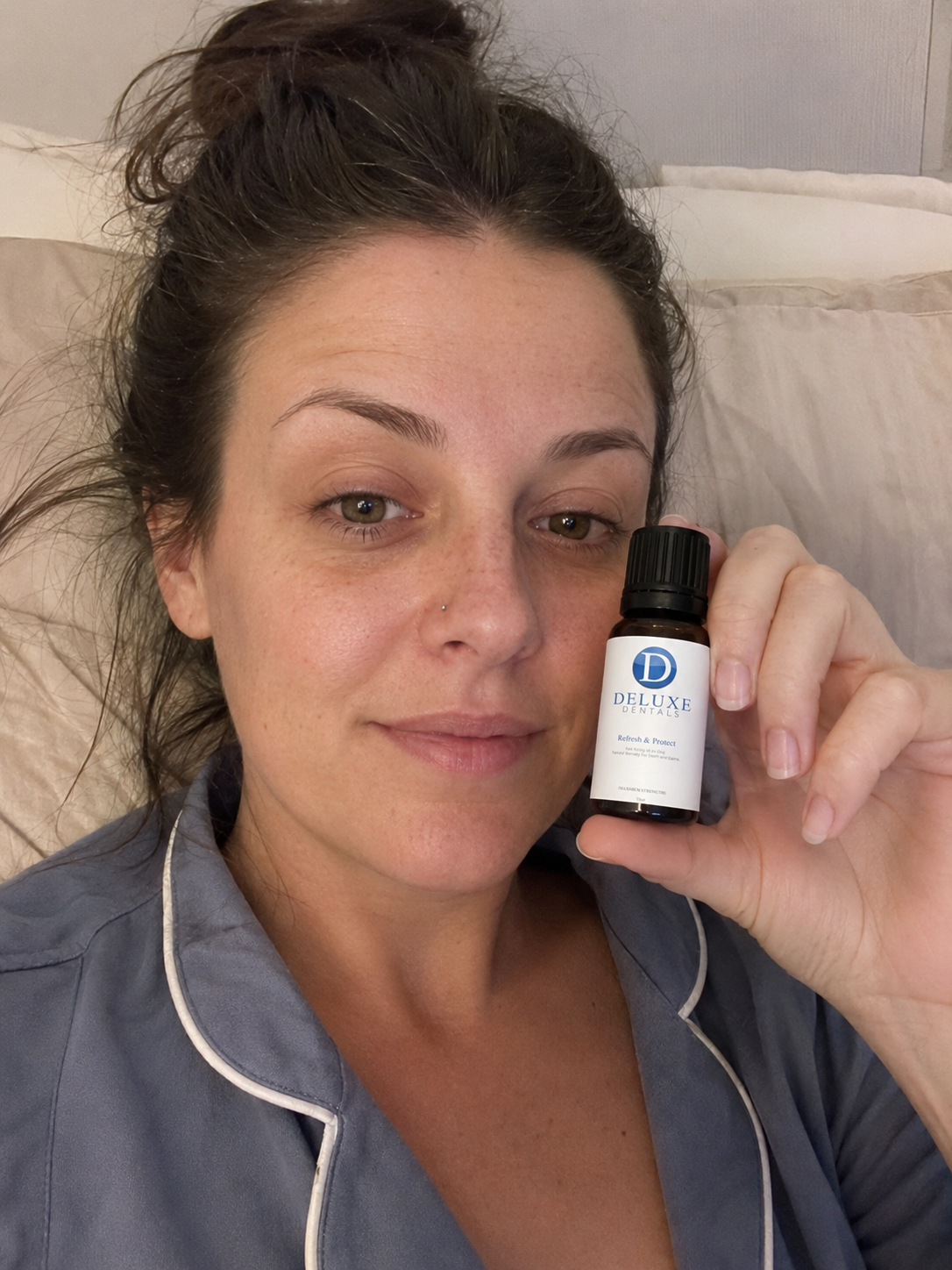 Customer holding the Refresh & Protect bottle while sitting up in bed.