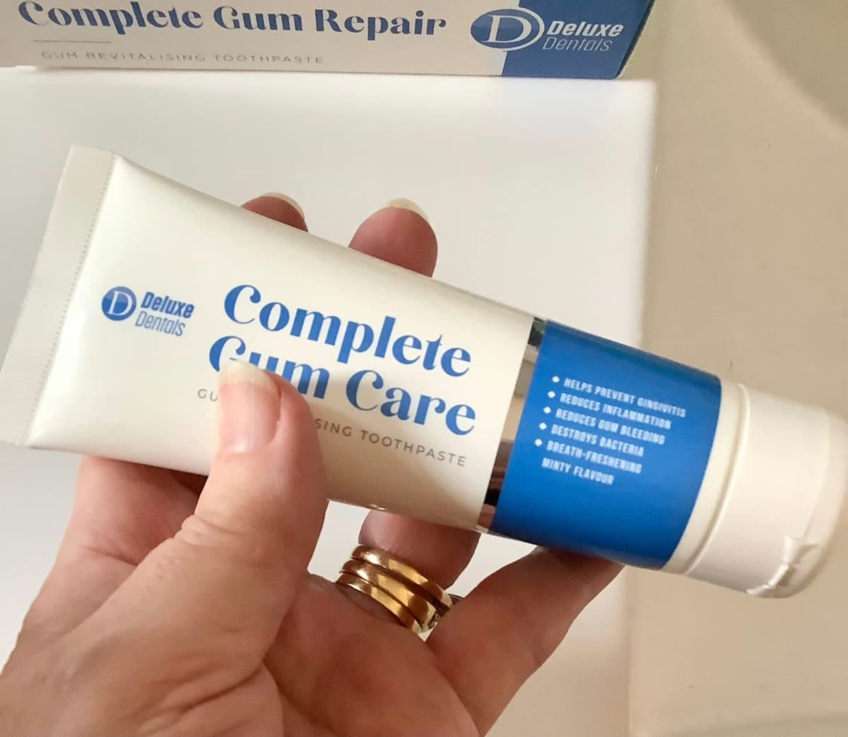 Customer holding the Complete Gum Care toothpaste tube and box.