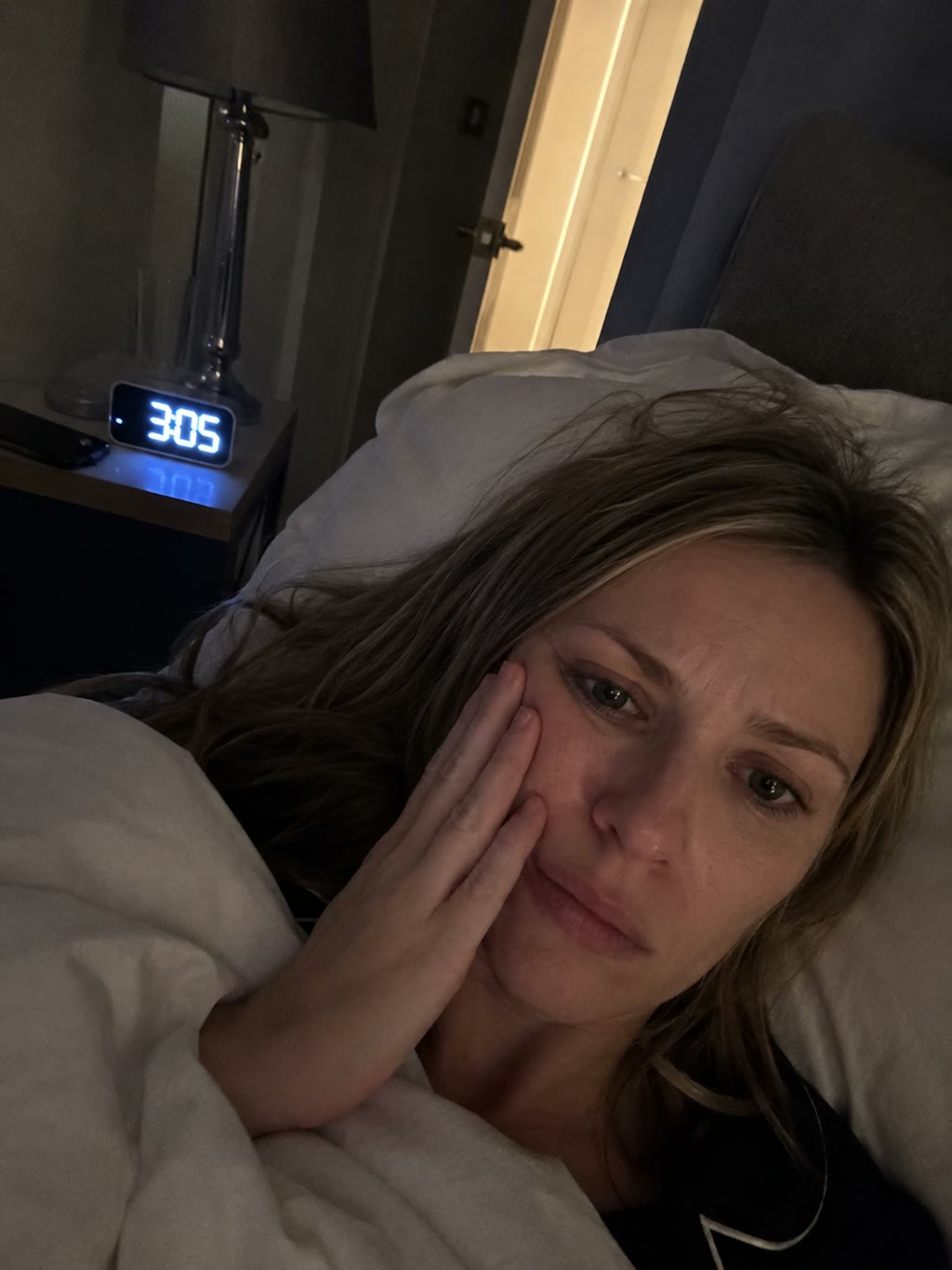 Adult holding their jaw in pain at night.