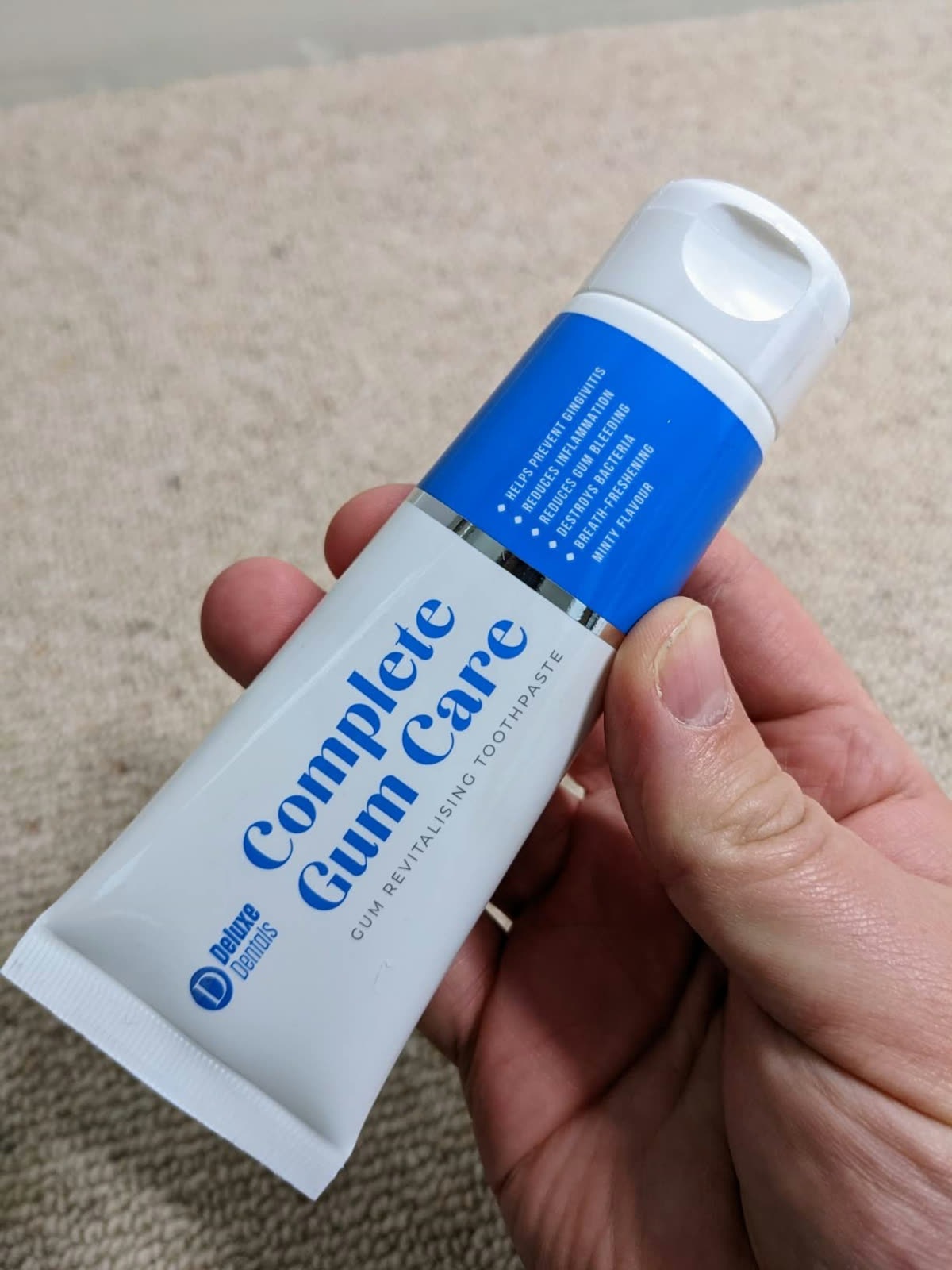 Customer holding the Complete Gum Care toothpaste tube in hand.