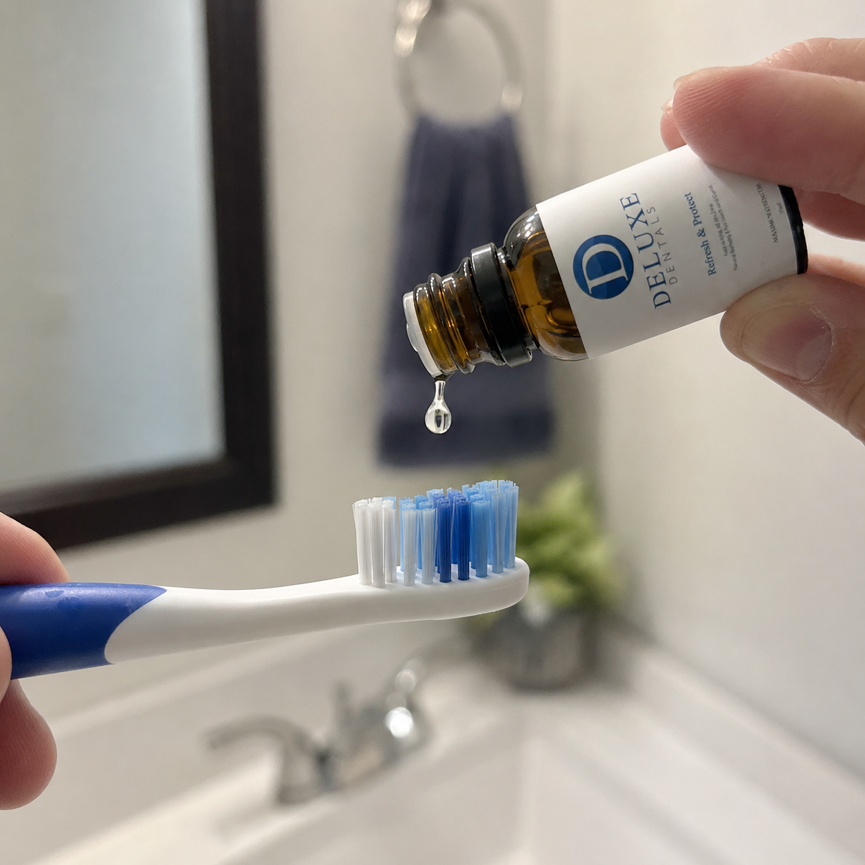 Drop of Deluxe Dentals oil falling onto a toothbrush.